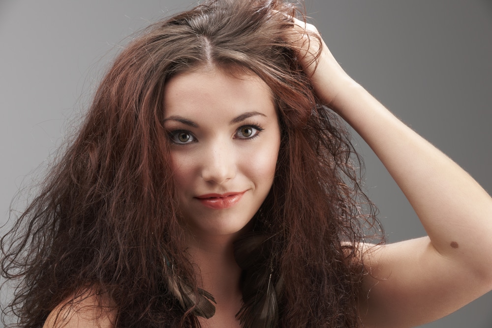 woman grabbing her frizzy, tangled hair - how to get the frizz out of human hair wigs