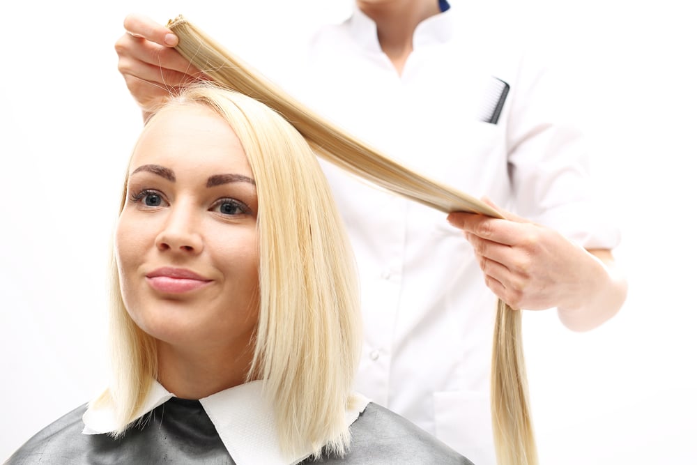 Woman in a salon getting blonde hair extensions placed - how do hair extensions work