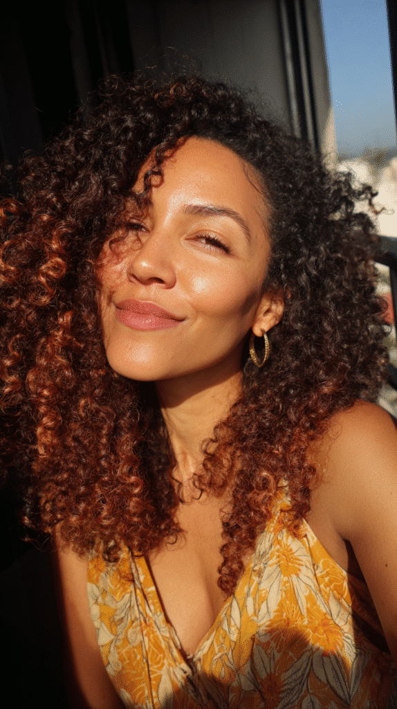 Voluminous afro dyed bright fire engine red with a park background softly blurred.