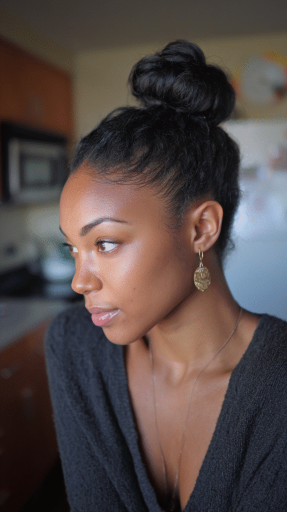Woman with a sleek high bun, highlighting her facial features and neck.