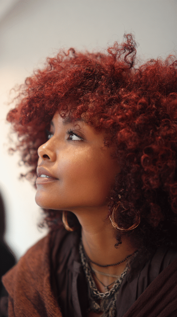 Ruby red blowout with stretched volume and soft curls in an art gallery.