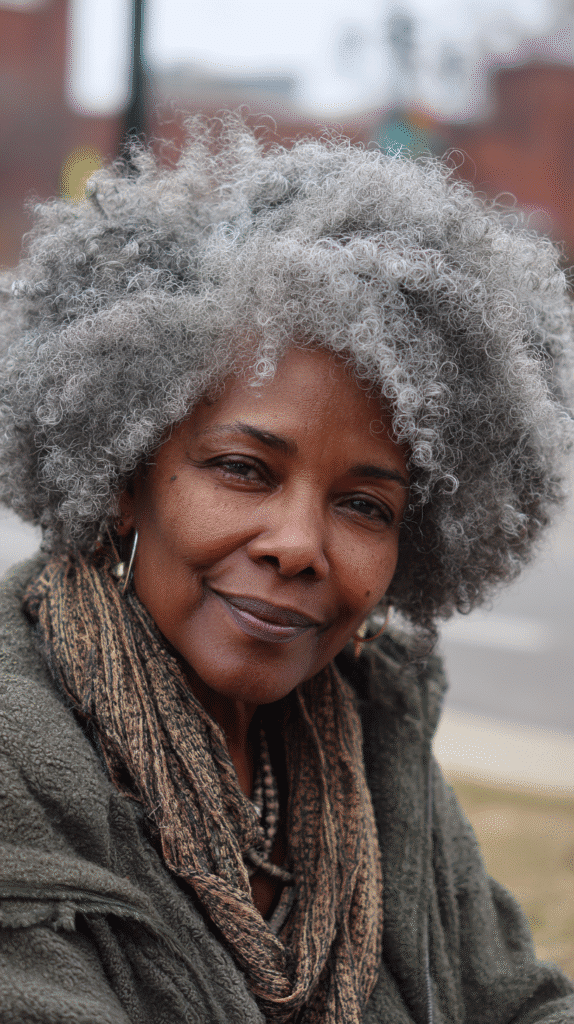 Voluminous curly afro styled in salt and pepper tones.