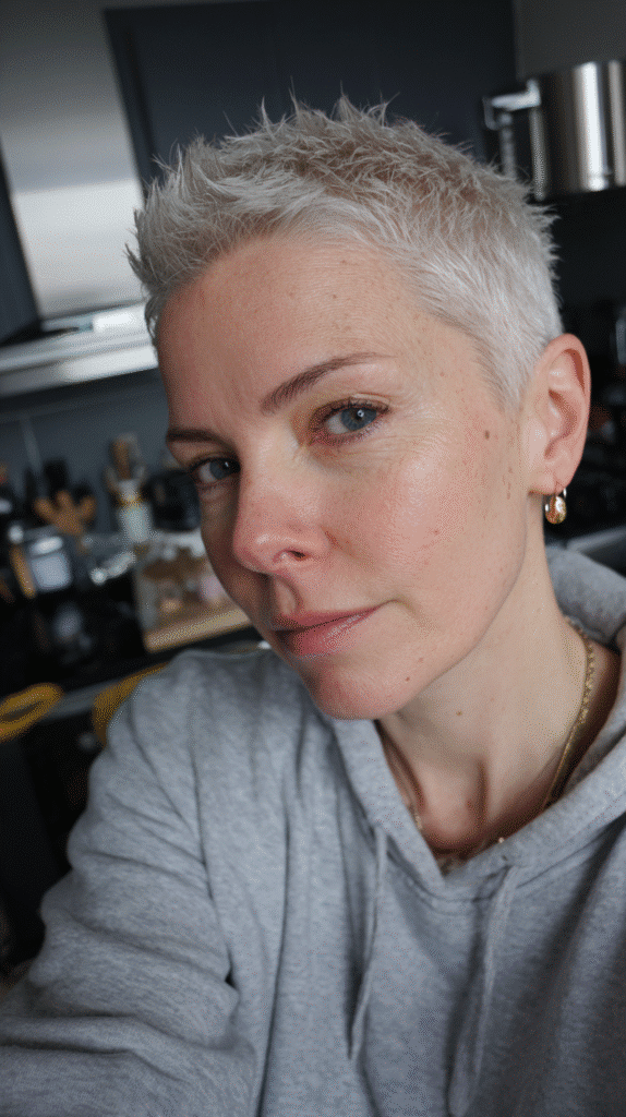 A 40-year-old woman with a silver spiked pixie cut, captured in a modern kitchen with focus on the icy hair texture.