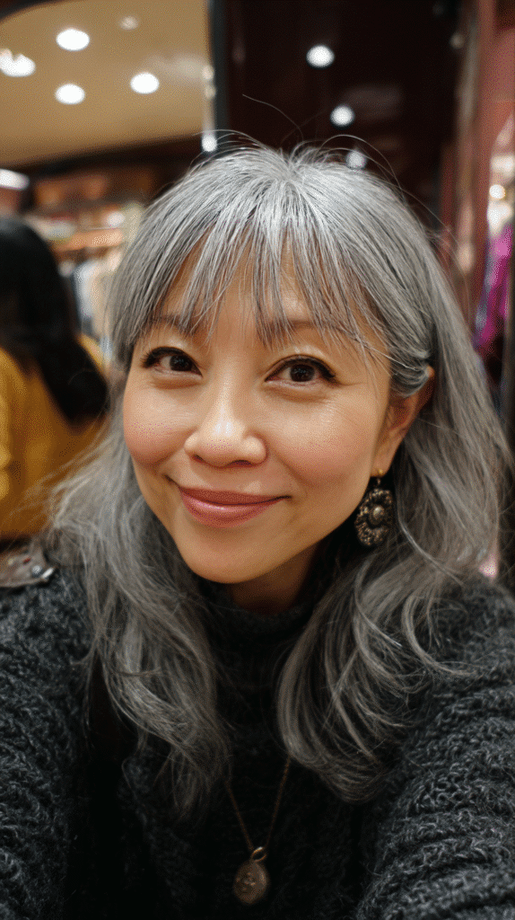 Wispy bangs paired with salt and pepper layered hair.