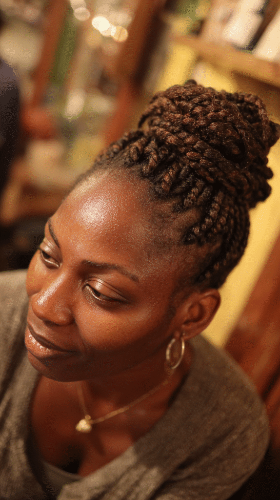 Woman with box braids gathered into a high, structured bun.