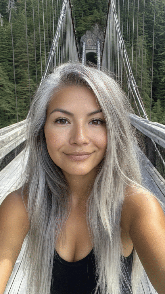 Woman with ombre hair transitioning from dark roots to grey blonde ends.