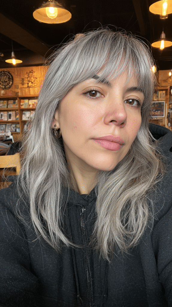 Woman with grey blonde hair and curtain bangs styled softly around the face.