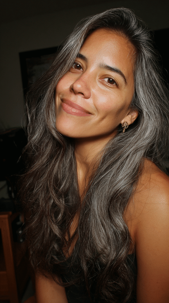 A woman with dark brown wavy hair featuring bold silver money pieces that frame her face.