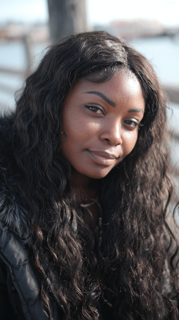 African-American woman with a water wave wig and middle part near a peaceful lakeside.